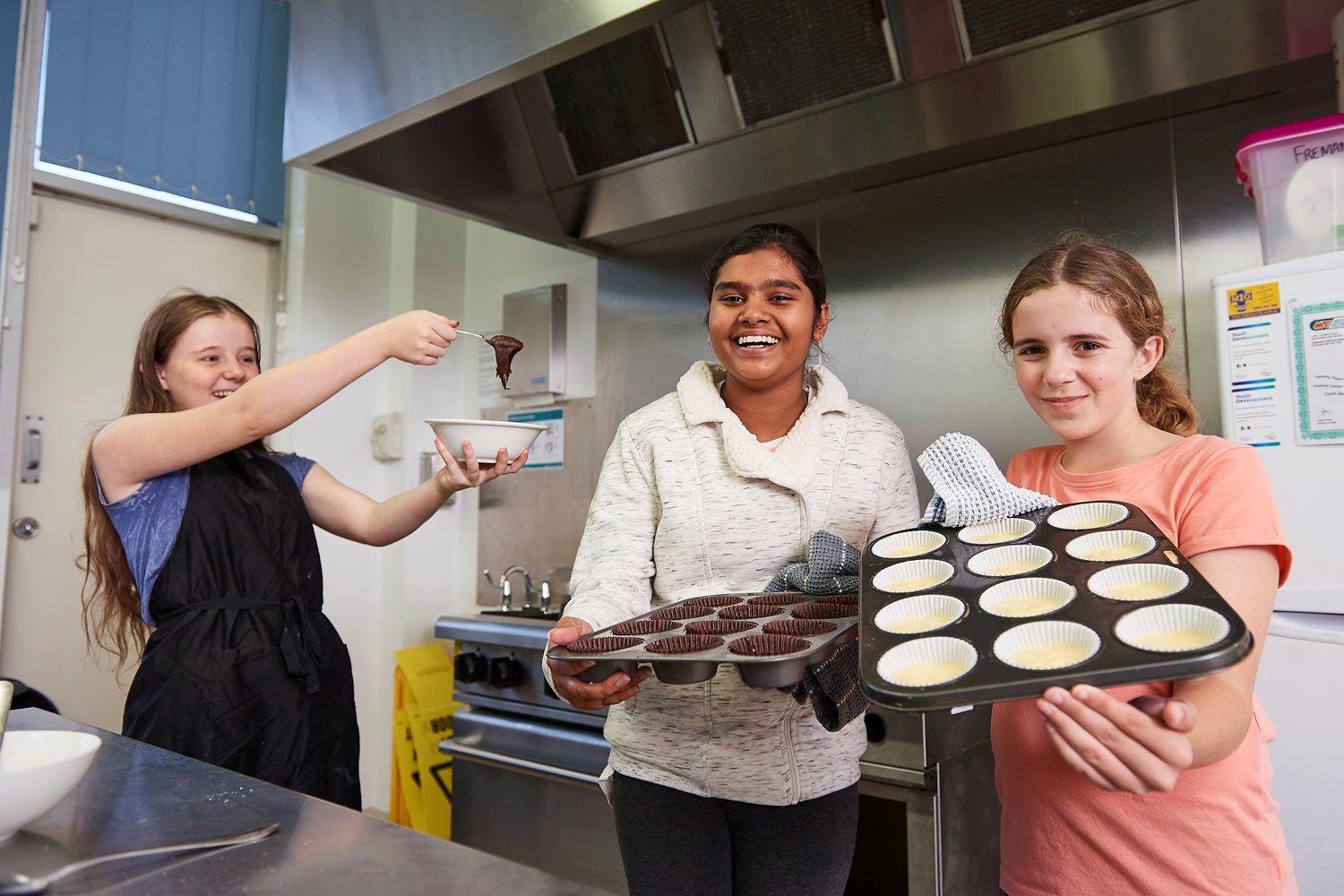 Youths showing their baking in kitchen.